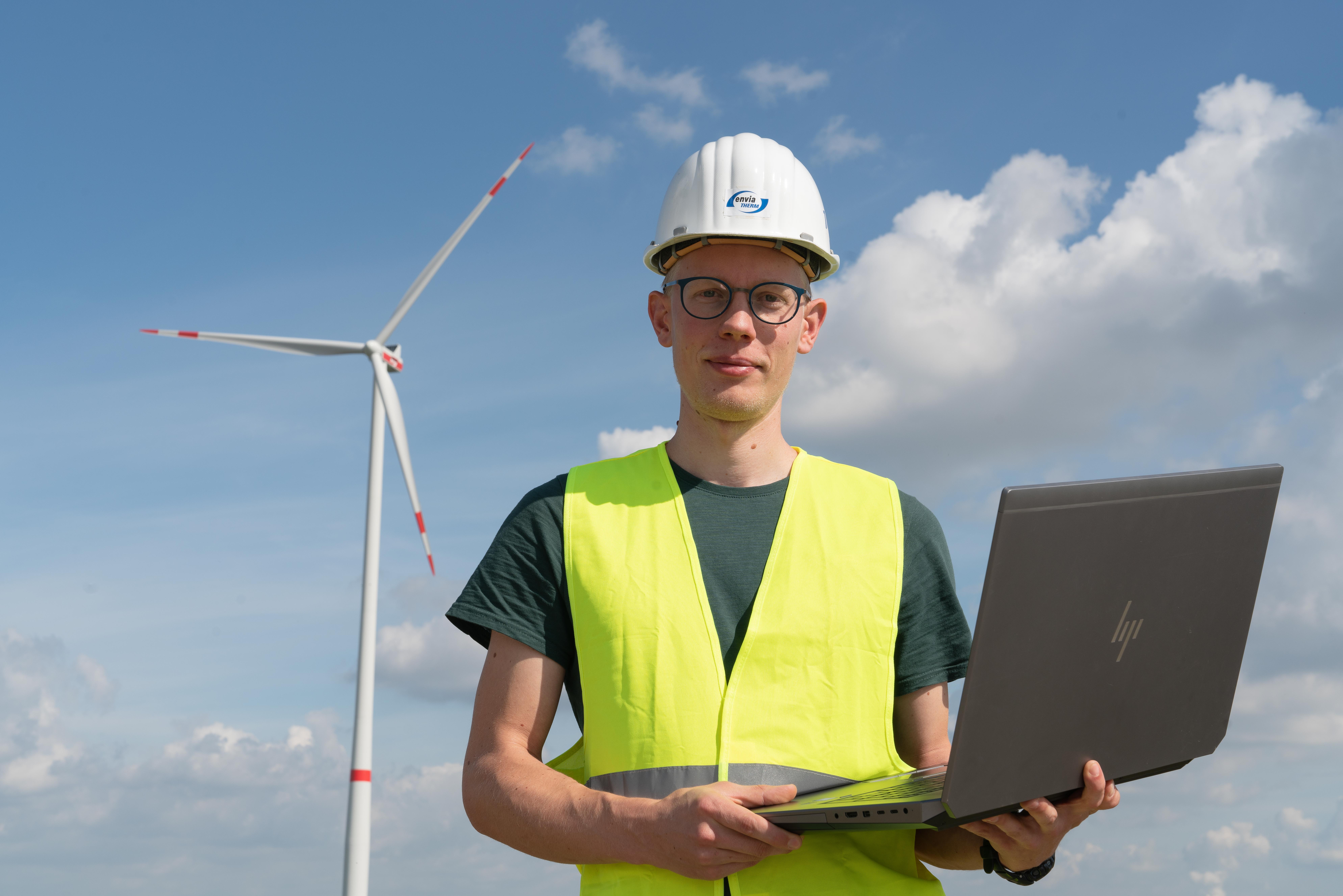 Mitarbeiter vor Windrad mit Laptop