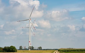 zwei Windraeder auf der Wiese Das Bild zeigt eine ländliche Landschaft mit zwei großen Windkraftanlagen, die in einem offenen Feld stehen. Ein unbefestigter Weg führt in Richtung der Windräder. Der Himmel ist teilweise bewölkt.