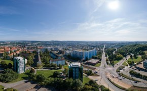 Panorama Plauen Wohnungsbau Das Bild zeigt eine Panoramaaufnahme einer Stadtlandschaft bei Tageslicht. Der Himmel ist klar und blau, die Sonne steht hoch oben rechts im Bild.