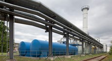 Außenaufnahme des Heizkraftwerks Guben, im Vordergrund ein Versorgungsrohrsystem und blaue Tanks  Außenaufnahme des Heizkraftwerks Guben, im Vordergrund ein Versorgungsrohrsystem und blaue Tanks