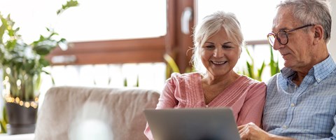 Mann und Frau sitzen auf dem Sofa und werfen auf dem Laptop einen Blick ins Kundenportal Mann und Frau sitzen auf dem Sofa und werfen auf dem Laptop einen Blick ins Kundenportal
