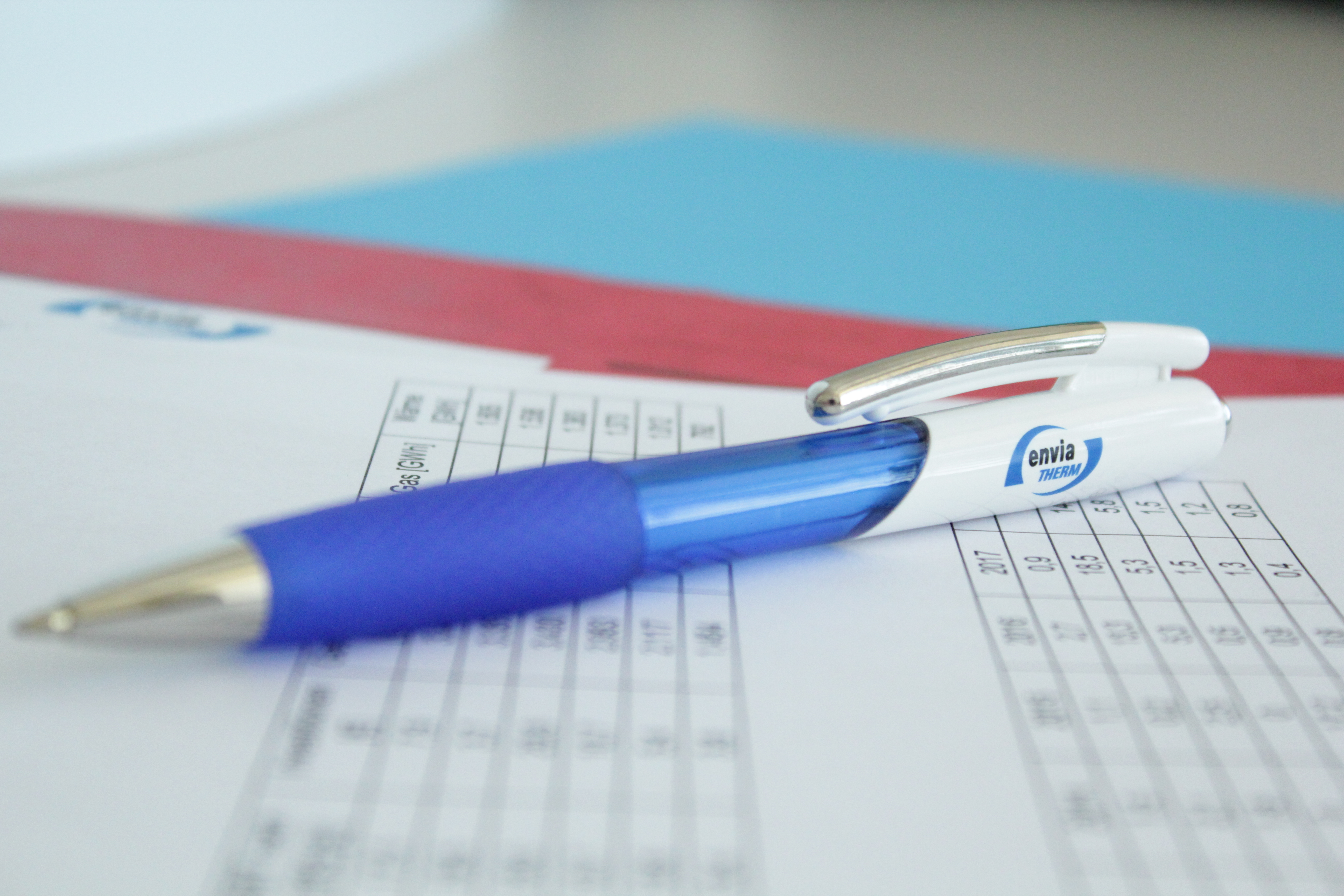 Kugelschreiber mit envia THERM-Logo liegt auf Blatt mit Tabellen