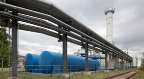 Außenaufnahme des Heizkraftwerks Guben, im Vordergrund ein Versorgungsrohrsystem und blaue Tanks  Außenaufnahme des Heizkraftwerks Guben, im Vordergrund ein Versorgungsrohrsystem und blaue Tanks