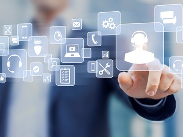 Service & Support Das Bild zeigt eine Person in einem Anzug, die mit schwebenden Symbolen interagiert, die verschiedene Dienste und Werkzeuge darstellen. Die Hand der Person ist ausgestreckt und berührt das Symbol mit einem Headset.